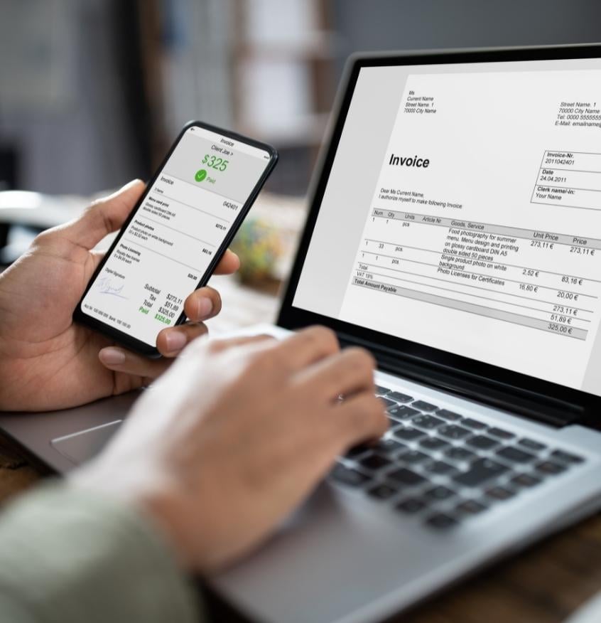 Businessman's Hands Working On Invoice On Laptop