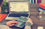 un comptable utilisant une calculatrice et un ordinateur dans le cadre de ses fonctions
