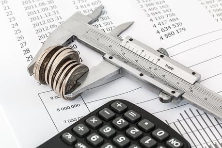 a calculator, ruler, coins, and balance sheet used to calculate small-business expenses